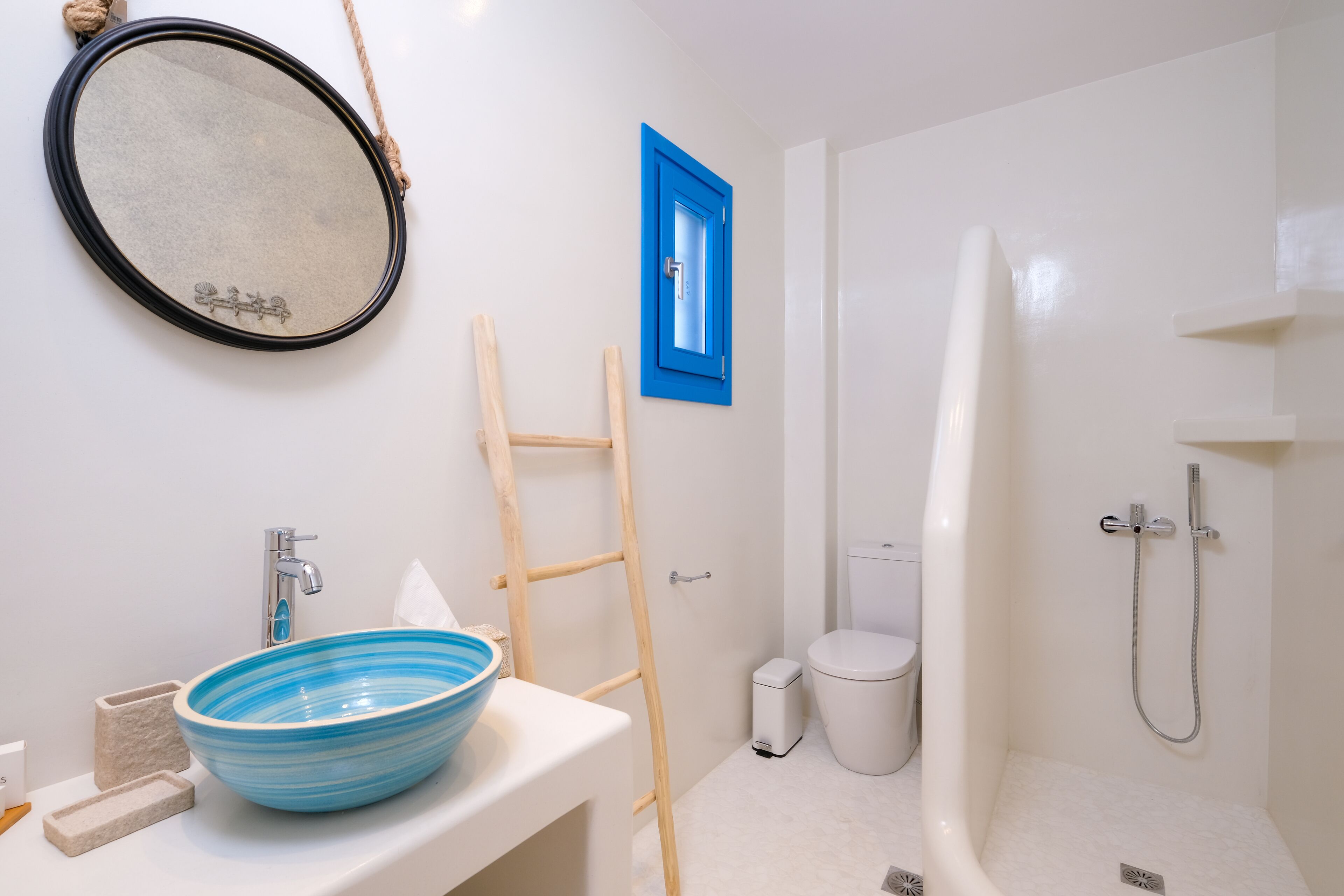 Un baño con lavamanos blanco, lavabo azul y un espejo.