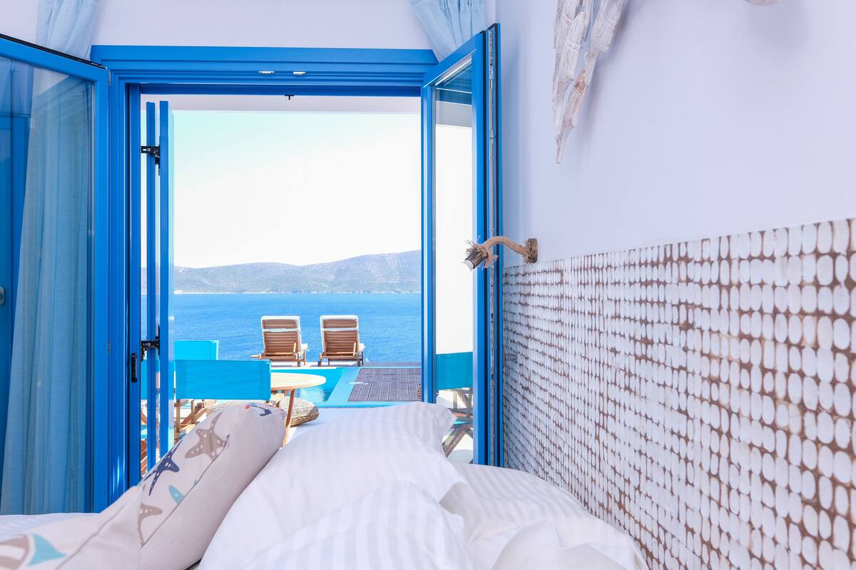 Une chambre avec un lit, une vue sur la mer et un balcon équipé de chaises.