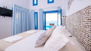 A hotel room with a bed, a TV, and a view of the sea.