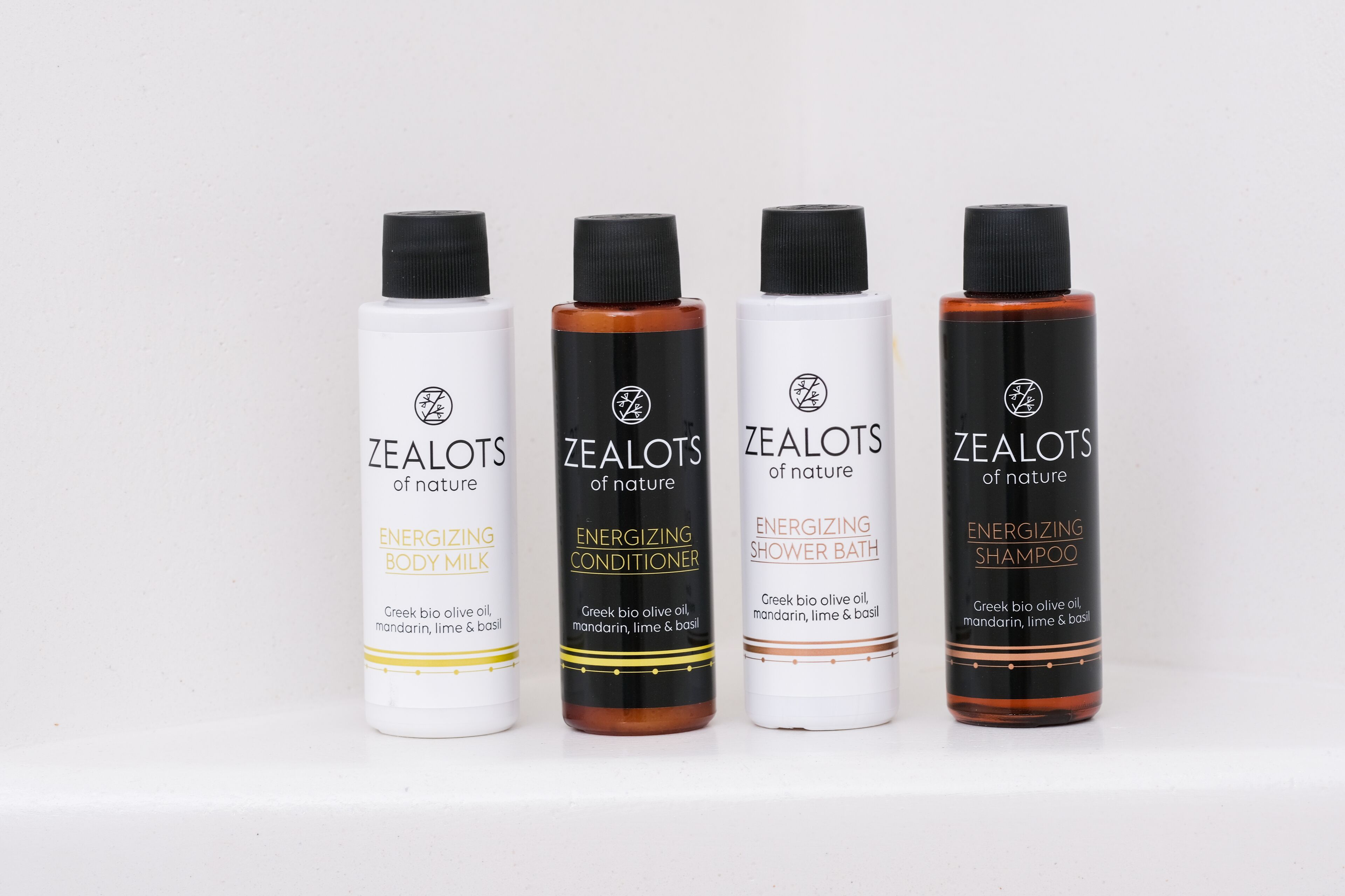 Four bottles of ZEALOTS of nature products: Energizing Body Milk, Energizing Conditioner, Energizing Shower Bath, and Energizing Shampoo.