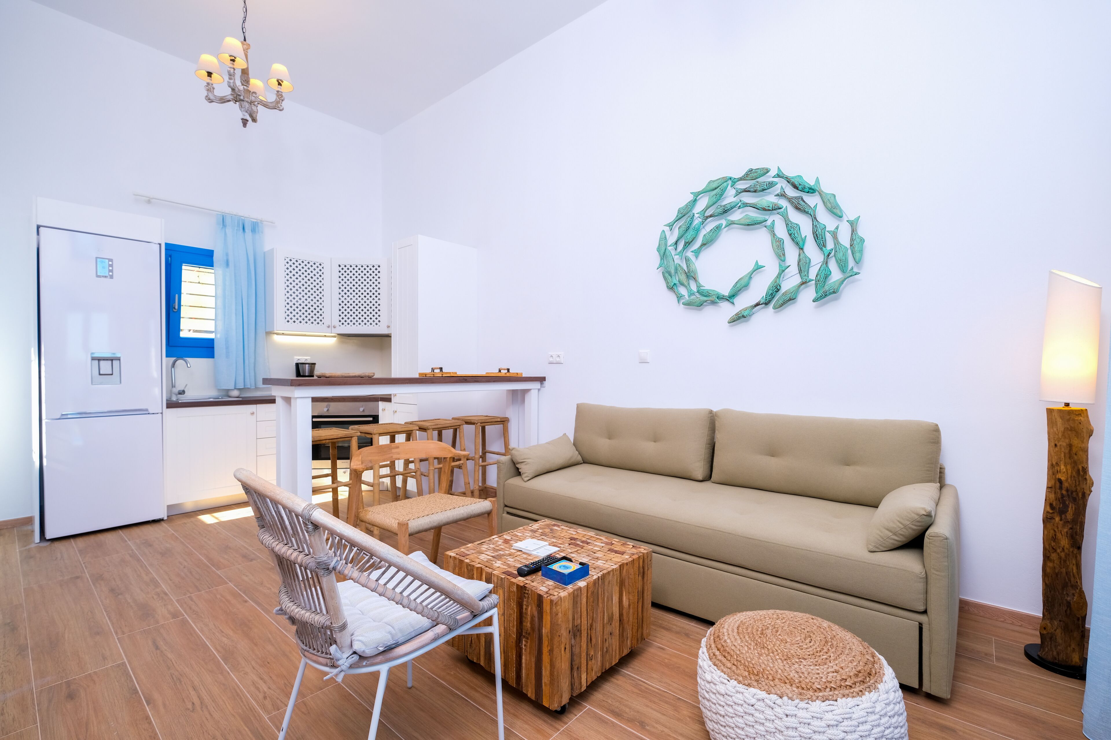 A modern living room with a beige sofa, a wooden coffee table, wicker chairs, and a decorative wall piece.