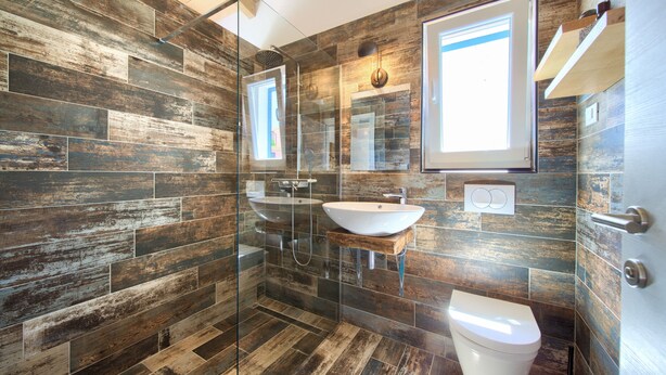 Een moderne badkamer met een glazen douchecabine, een wit wastafelmeubel en een toilet.