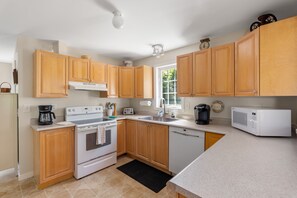 A modern kitchen with wooden cabinets, a stove, a dishwasher, and a microwave.