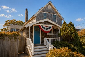 A two-story house with a blue door, white porch railing, and a chimney. - Sunset Cove: Waterfront living on the Annisquam River (Gloucester)
