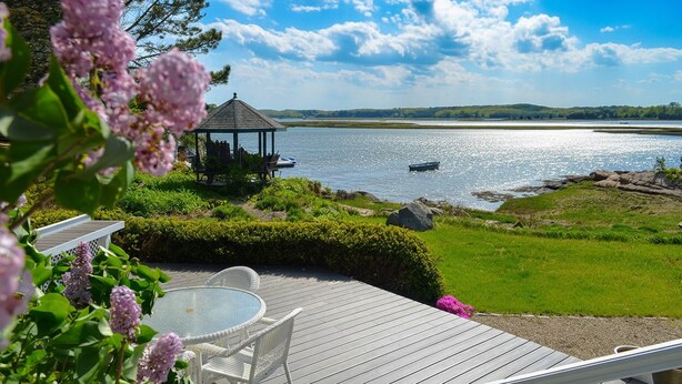 Une terrasse dotée d’un belvédère, d’une piscine et offrant une vue sur un lac où naviguent des bateaux.