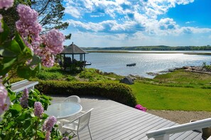 Una terraza con un pabellón, una piscina y vistas a un lago con barcos.