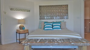 Une chambre à coucher comprenant un lit, une table de chevet, une lampe, un panneau décoratif fixé au mur et une enseigne sur laquelle on peut lire « GLOUCESTER ».