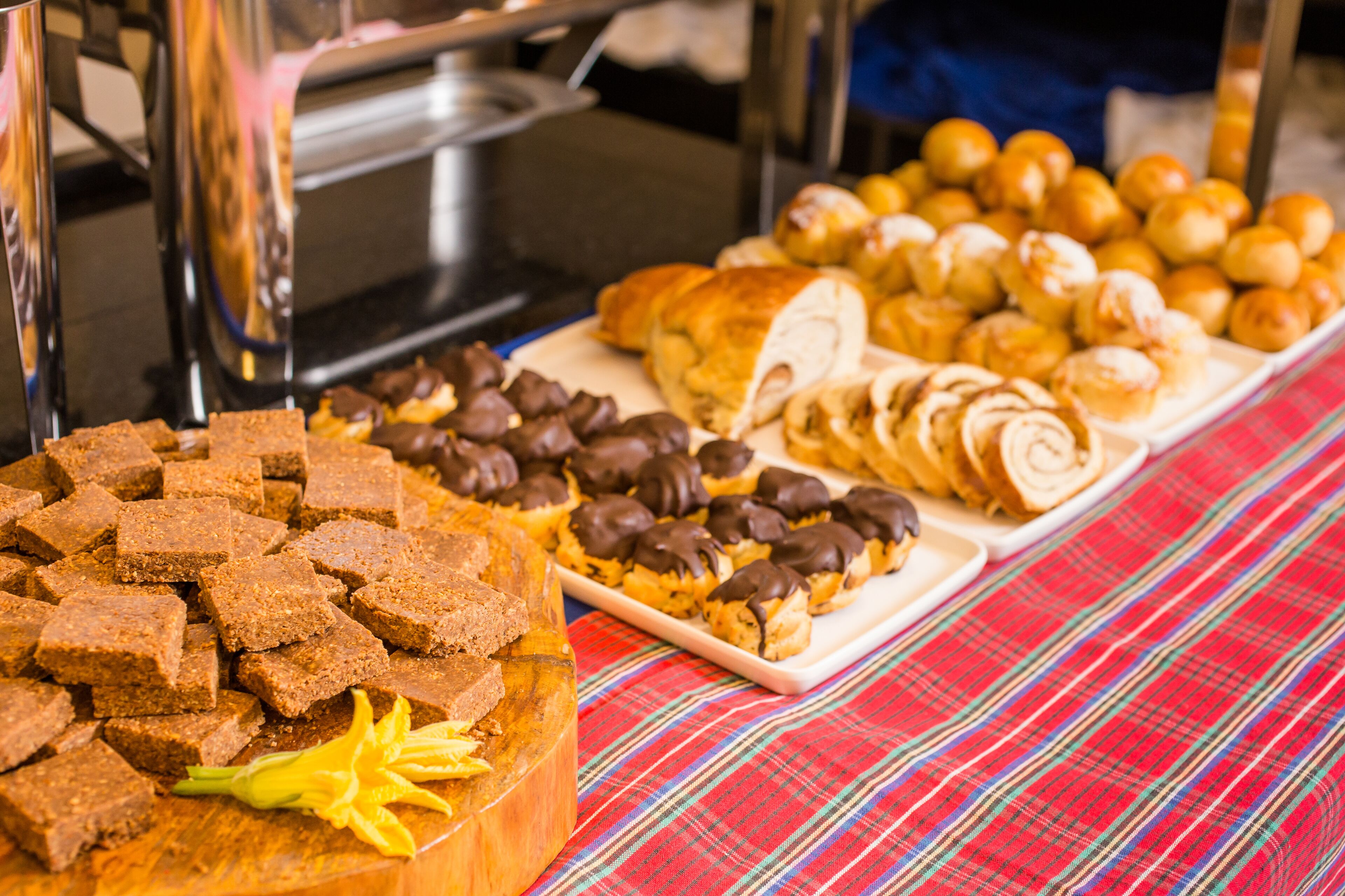 A buffet table with various baked goods including brownies, chocolate-topped pastries, and croissants.