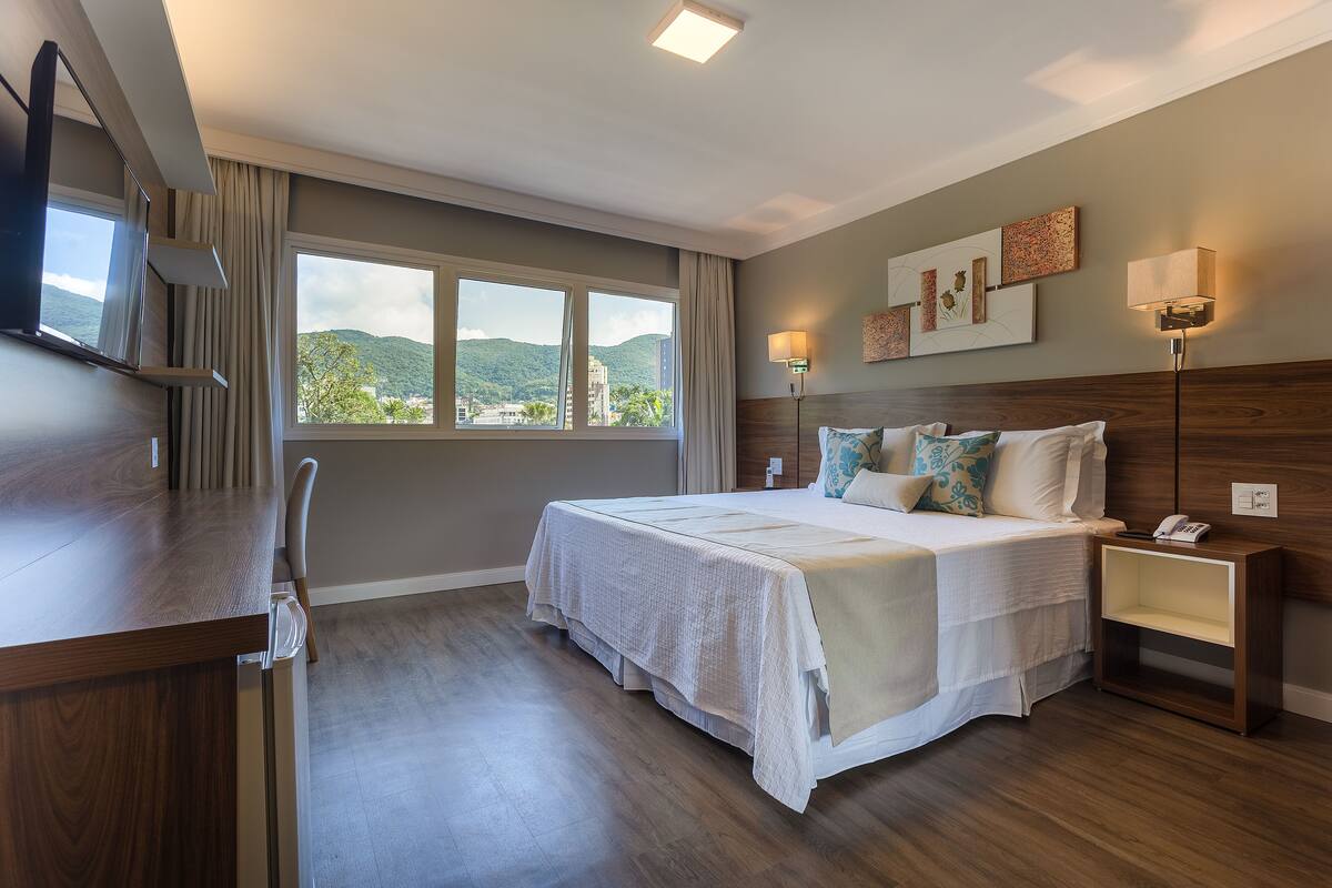 Une chambre d’hôtel avec un lit, une table de chevet, une lampe et un téléviseur.