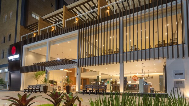 Een modern hotel met een ruime lobby, terras en een zichtbaar restaurant.