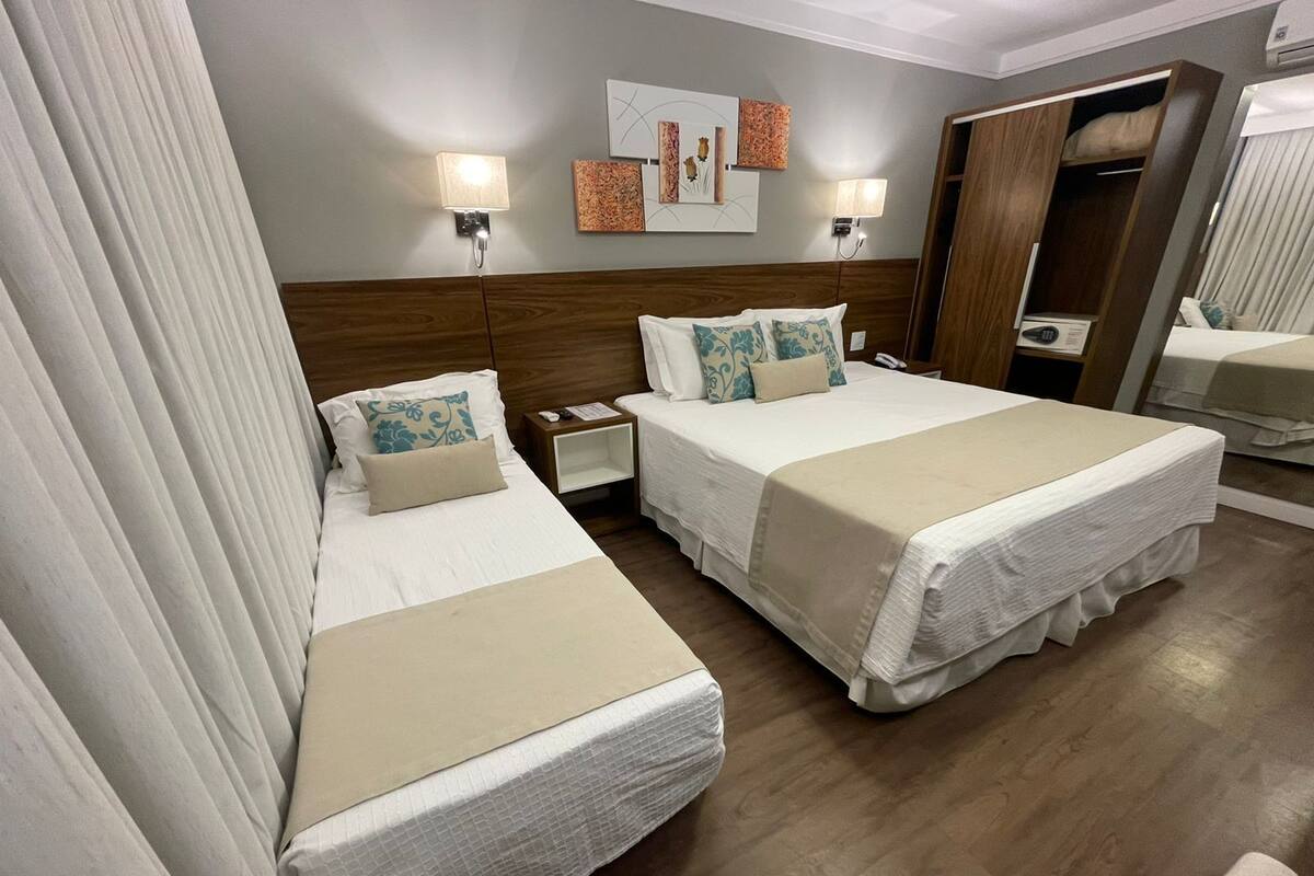 Une chambre d’hôtel avec deux lits, une tête de lit en bois, une table de chevet et une commode.