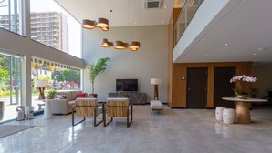 Een ruime lobby met een modern design, met een grote zithoek, een televisie en een receptiebalie.