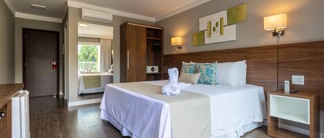 Une chambre d’hôtel avec un grand lit, des tables de chevet, une armoire et un balcon avec vue.