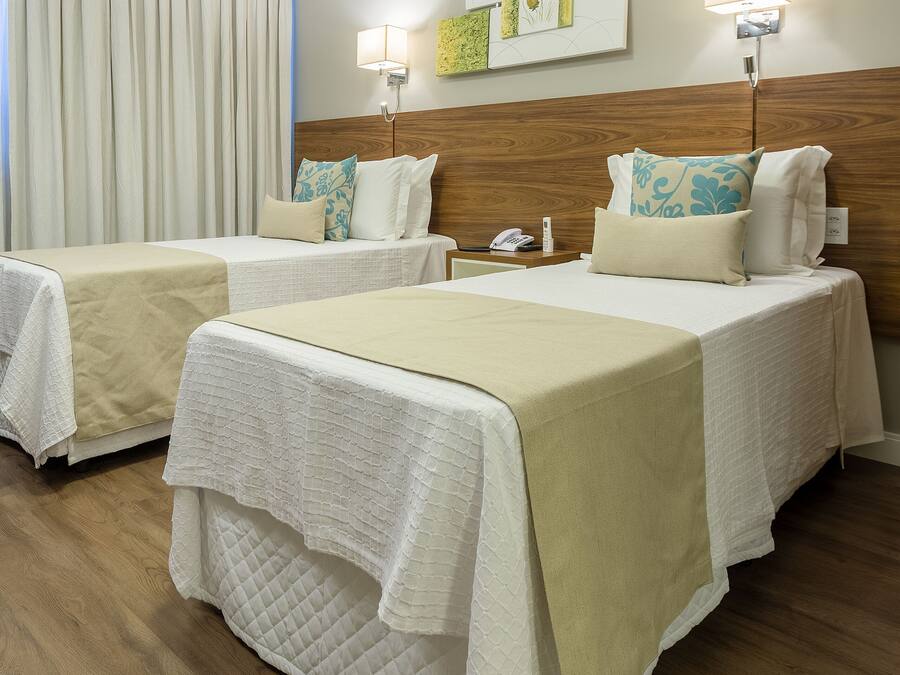 A hotel room with two beds, wooden flooring, and a wall-mounted artwork.