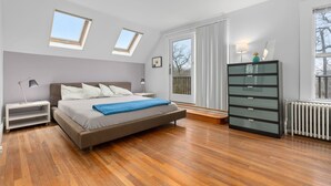 A bedroom with a bed, nightstands, a dresser, a skylight, and a window. - Helena House: Charming and serene, close to Plum Cove Beach (Gloucester)