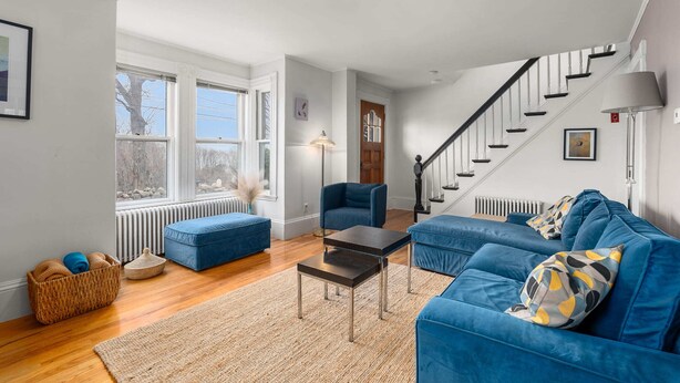 A living room with a blue sofa, a small table, a lamp, and a staircase. - Helena House: Charming and serene, close to Plum Cove Beach (Gloucester)