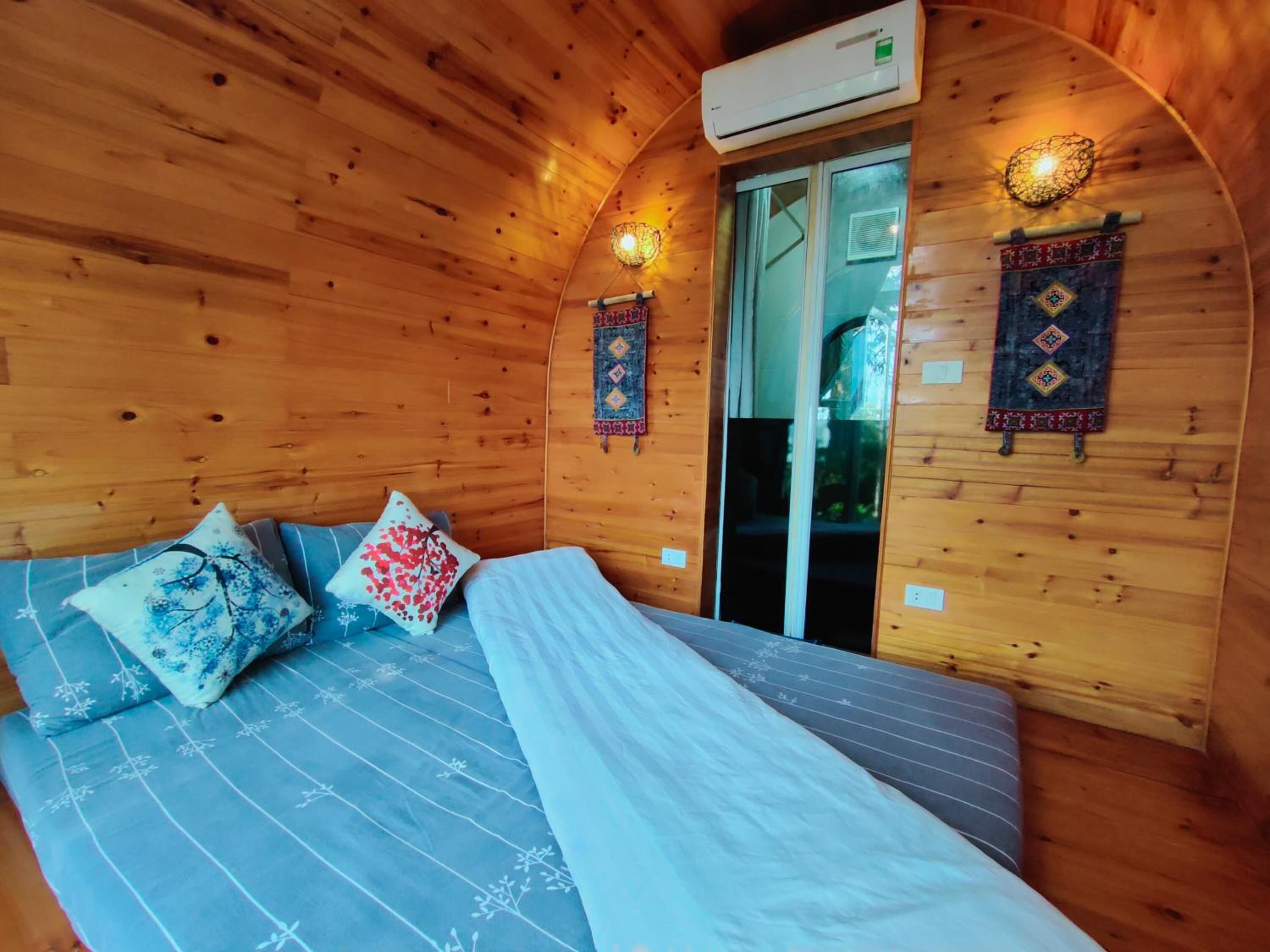 A cozy wooden room with a bed, a window, and a wall-mounted air conditioner.