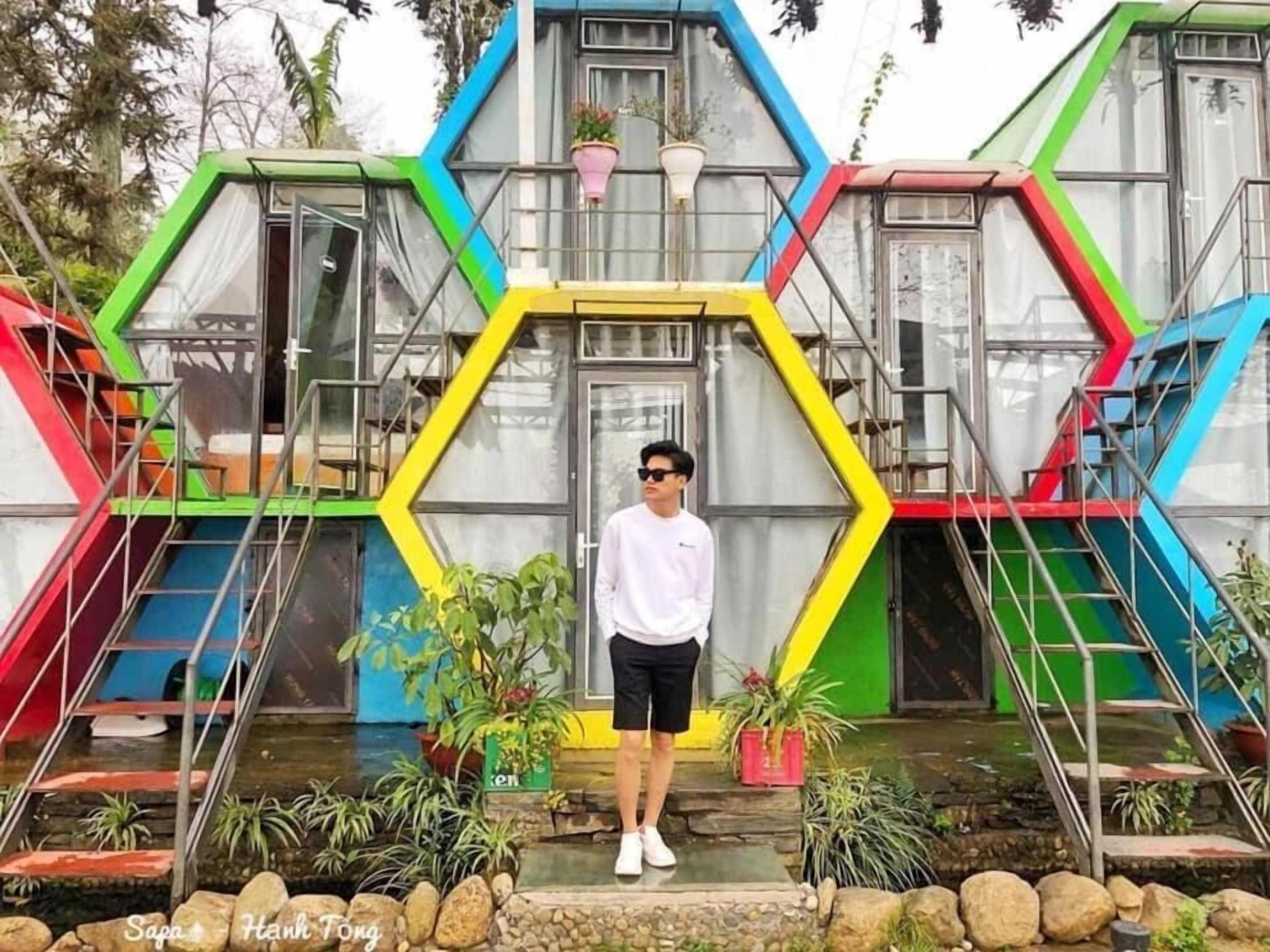 A person standing in front of a colorful, hexagonal structure with multiple levels and staircases.
