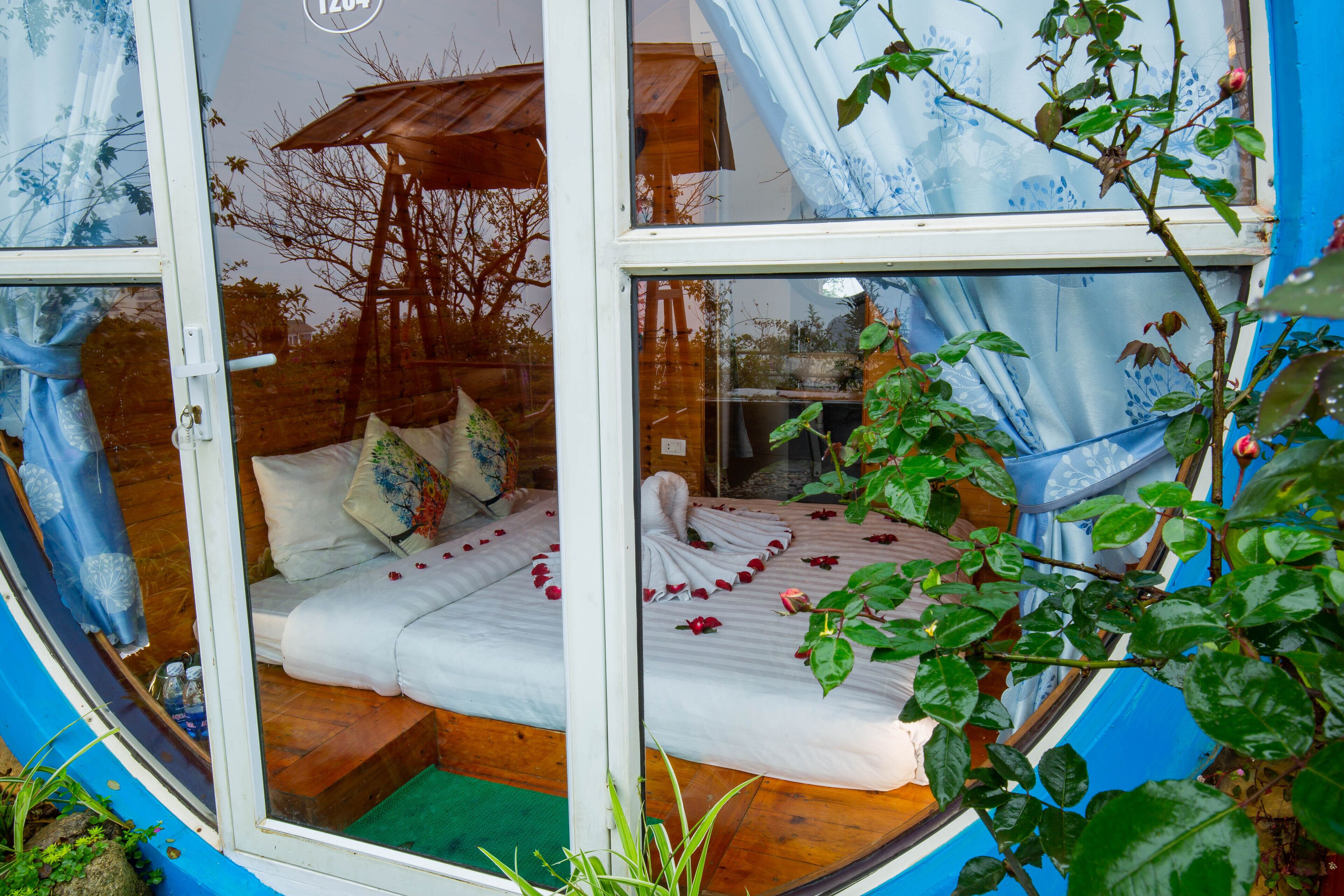 A cozy room with a bed, a wooden ladder, and a window with curtains.