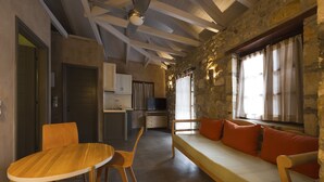 Un interior acogedor con una mesa y sillas de madera, un sofá con cojines naranja y una pared de piedra.