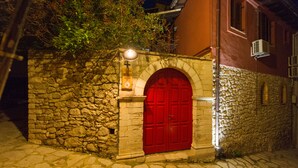 Un edificio de piedra con una puerta roja y un letrero encima.