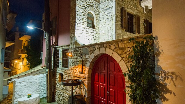 Un edificio de piedra con una puerta roja y una planta grande en maceta.