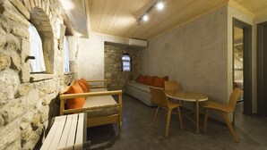 Una habitación acogedora con pared de piedra, muebles de madera, un arco de piedra y una ventana con persianas.