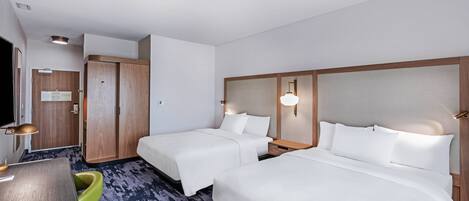 A hotel room with two beds, a desk, a chair, a wardrobe, and a television.