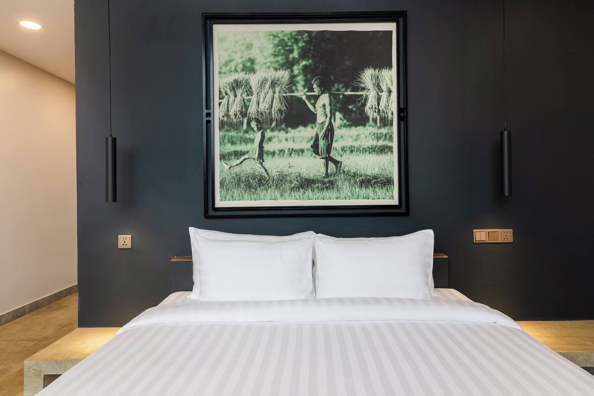 A bedroom with a bed, a framed picture on the wall, and a nightstand.