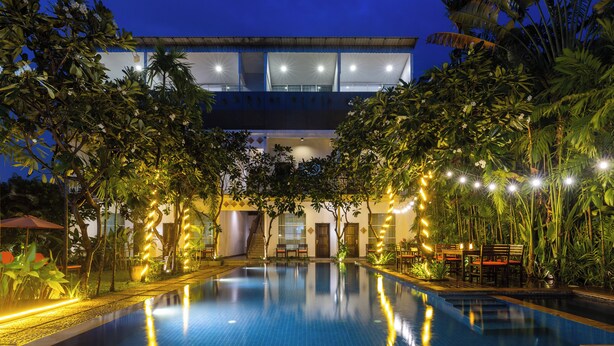 A swimming pool with a reflection of the building and trees, surrounded by well-lit outdoor seating areas. -  Angkor Serenity Hotel Siem Reap (Siem Reap)