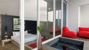 A modern hotel room with a large glass wall, a bed, a red sofa, and a small pool area. -  Angkor Serenity Hotel Siem Reap (Siem Reap)