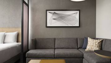 Una sala de estar moderna con un sofá gris, una mesa de centro de madera y una obra de arte abstracta enmarcada en la pared.