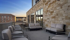 A rooftop patio with outdoor seating, stone walls, and large windows. - Hyatt Place Amarillo-West (Amarillo)