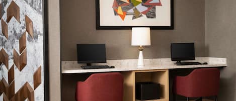 Un espacio de oficina moderno con dos escritorios, cada uno con un monitor de computadora, una lámpara y una silla.