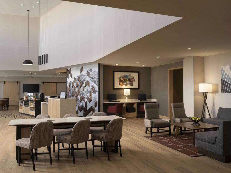 A modern hotel lobby with a dining area, a reception desk, and a seating area with a coffee table.
