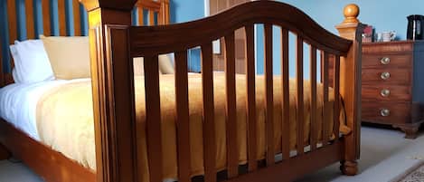 Un dormitorio con una cama de madera, un tocador y una puerta.