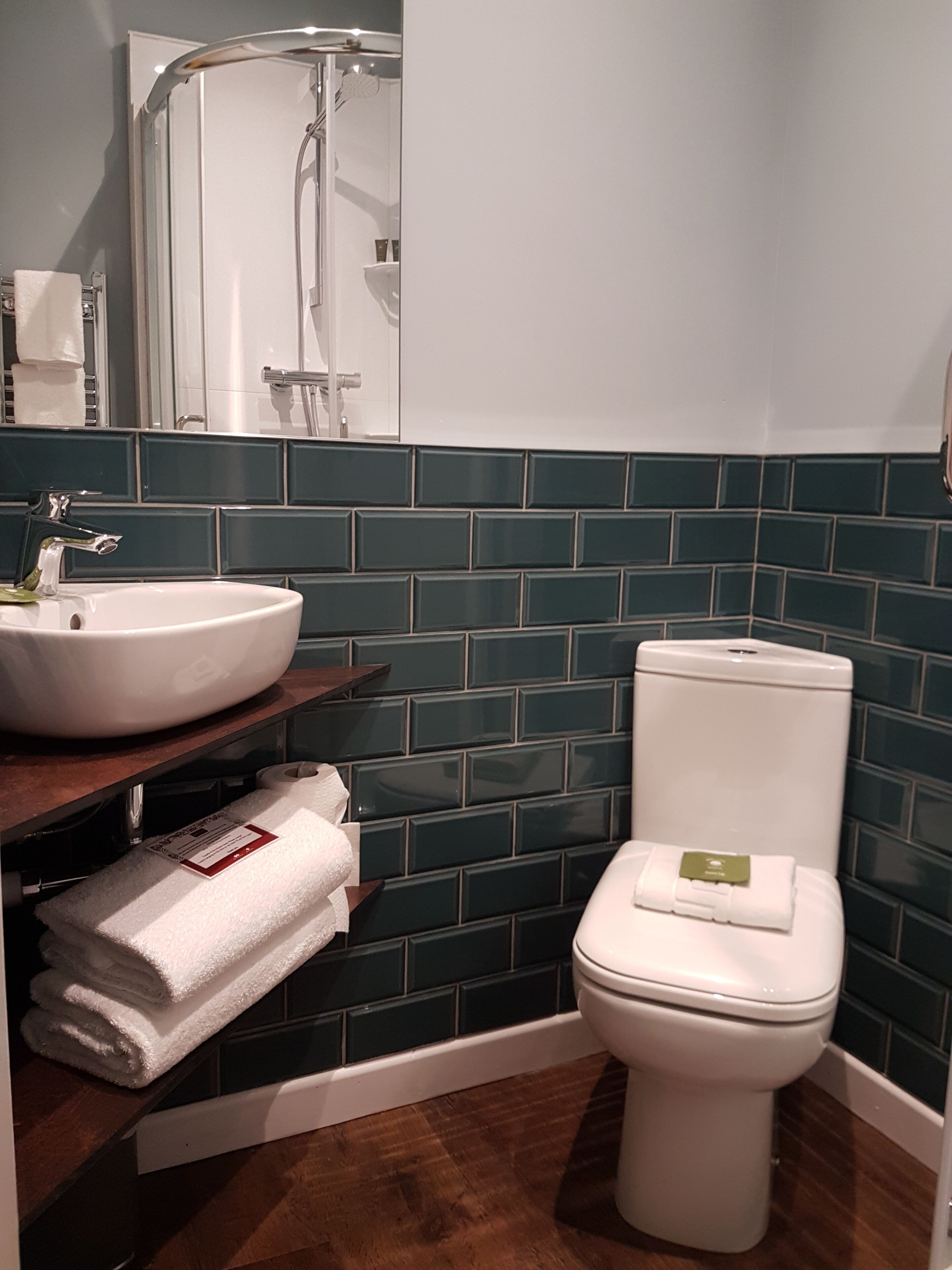 Et badeværelse med et hvidt håndvask, toilet og bruseområde.