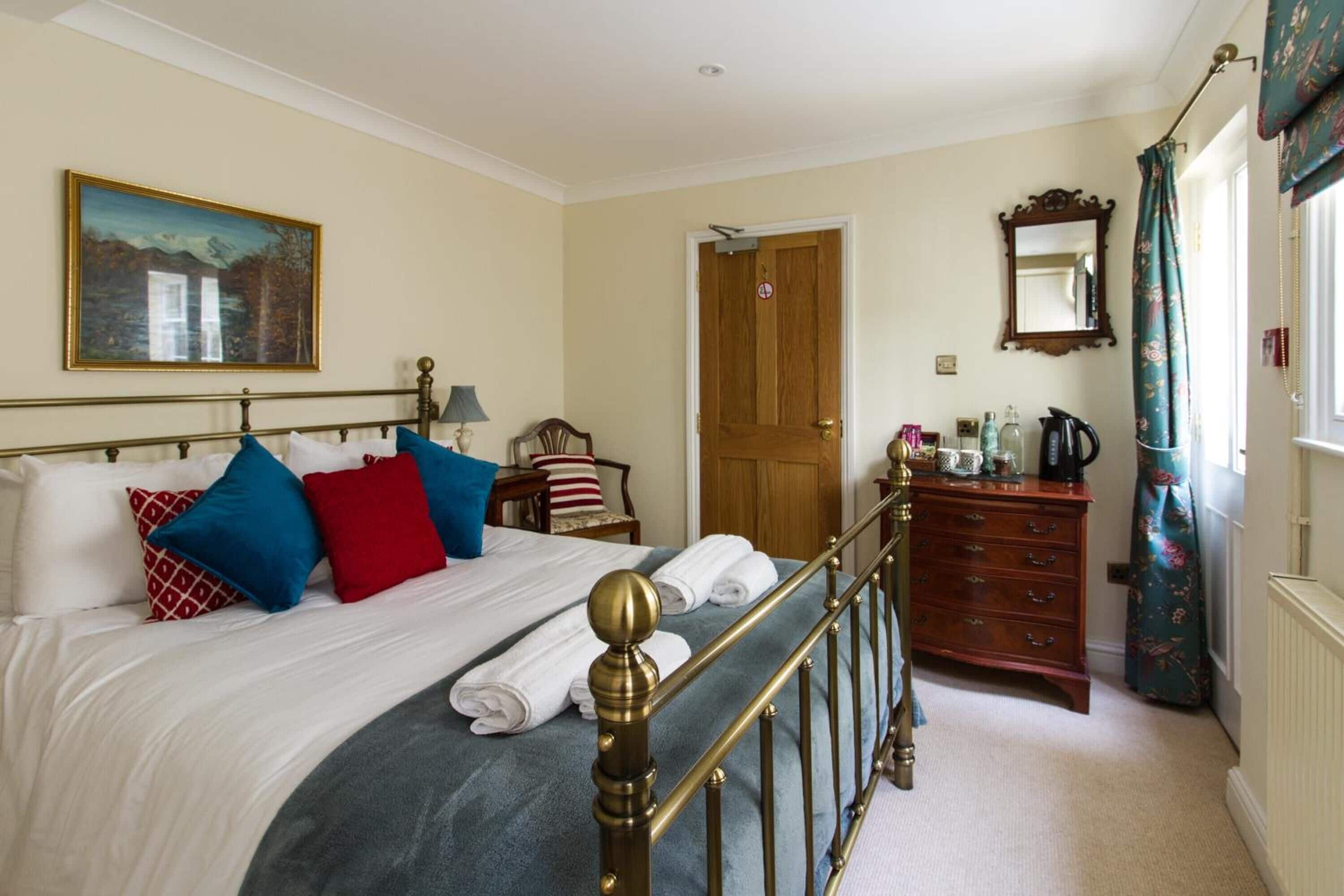 Une chambre bien rangée, avec un lit, une table de chevet, une commode et une porte.