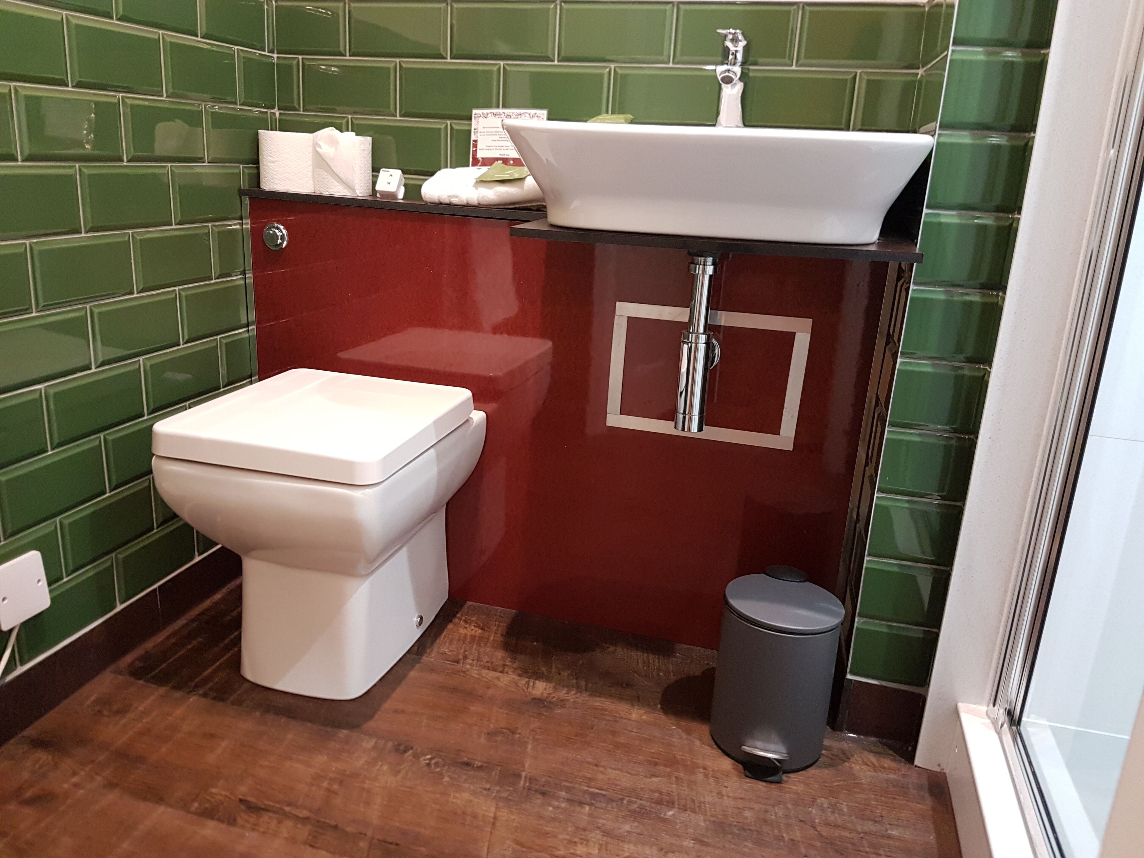 Een badkamer met een wit toilet, een wastafel en een prullenbak.
