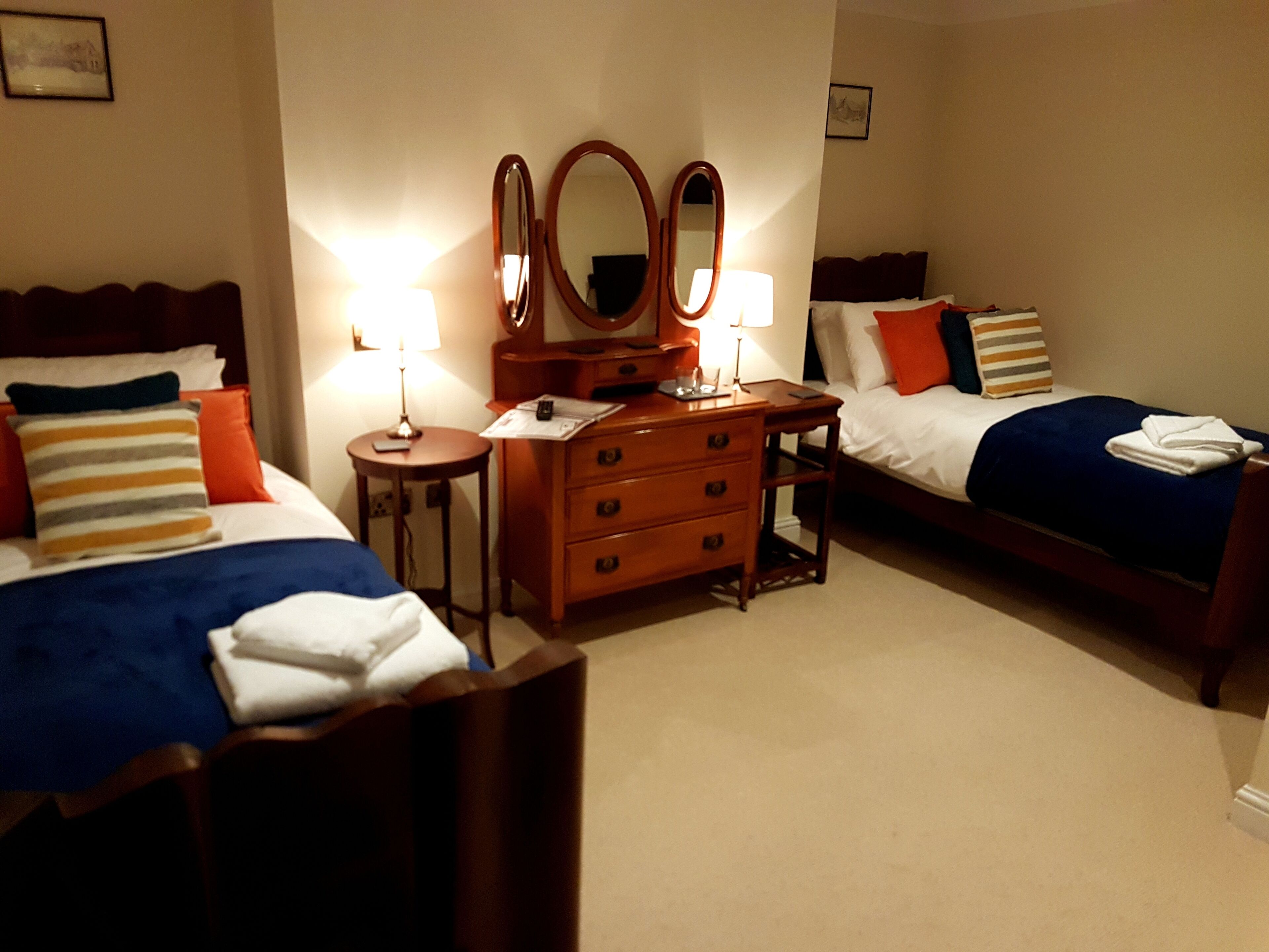 A hotel room with two beds, a dresser, and two bedside tables with lamps.
