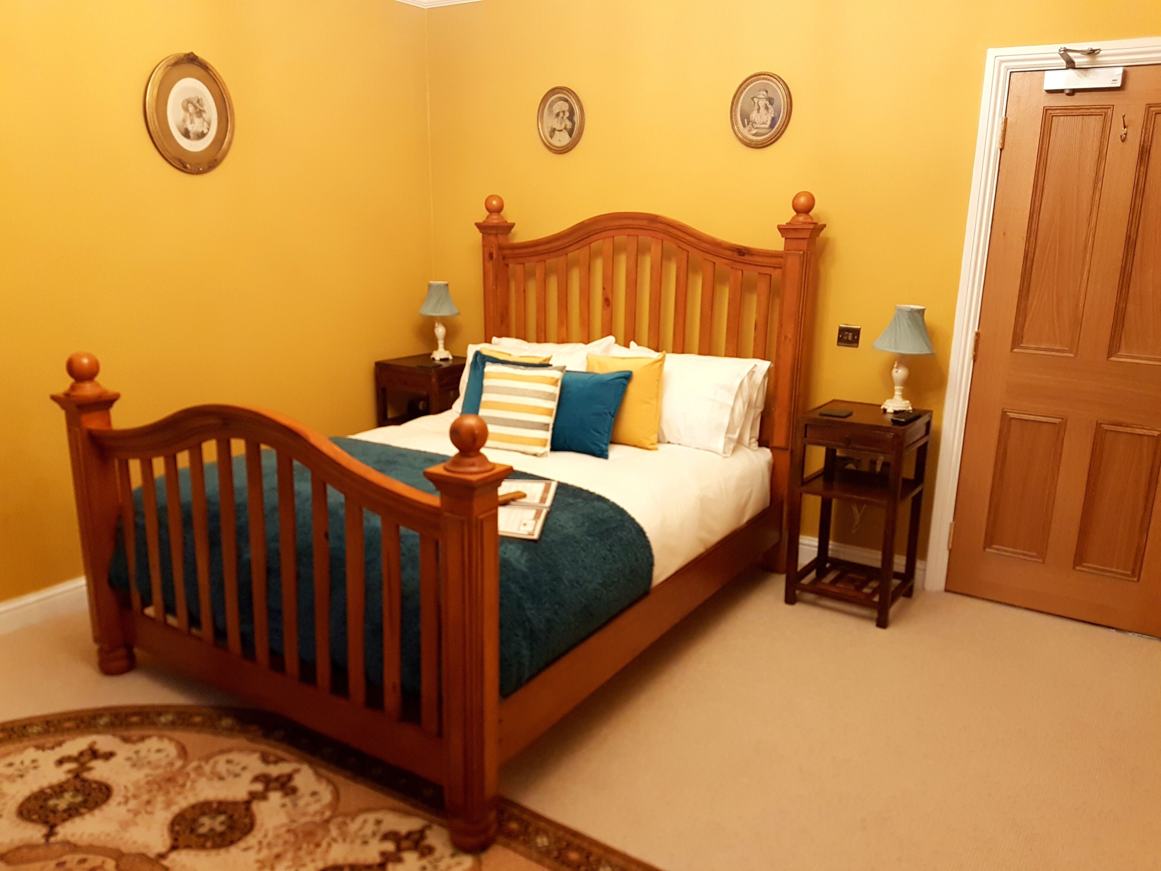 Un dormitorio con una cama de madera, dos mesitas de noche con lámparas y una puerta.