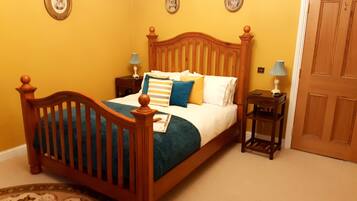 Un dormitorio con una cama de madera, dos mesitas de noche con lámparas y una puerta.