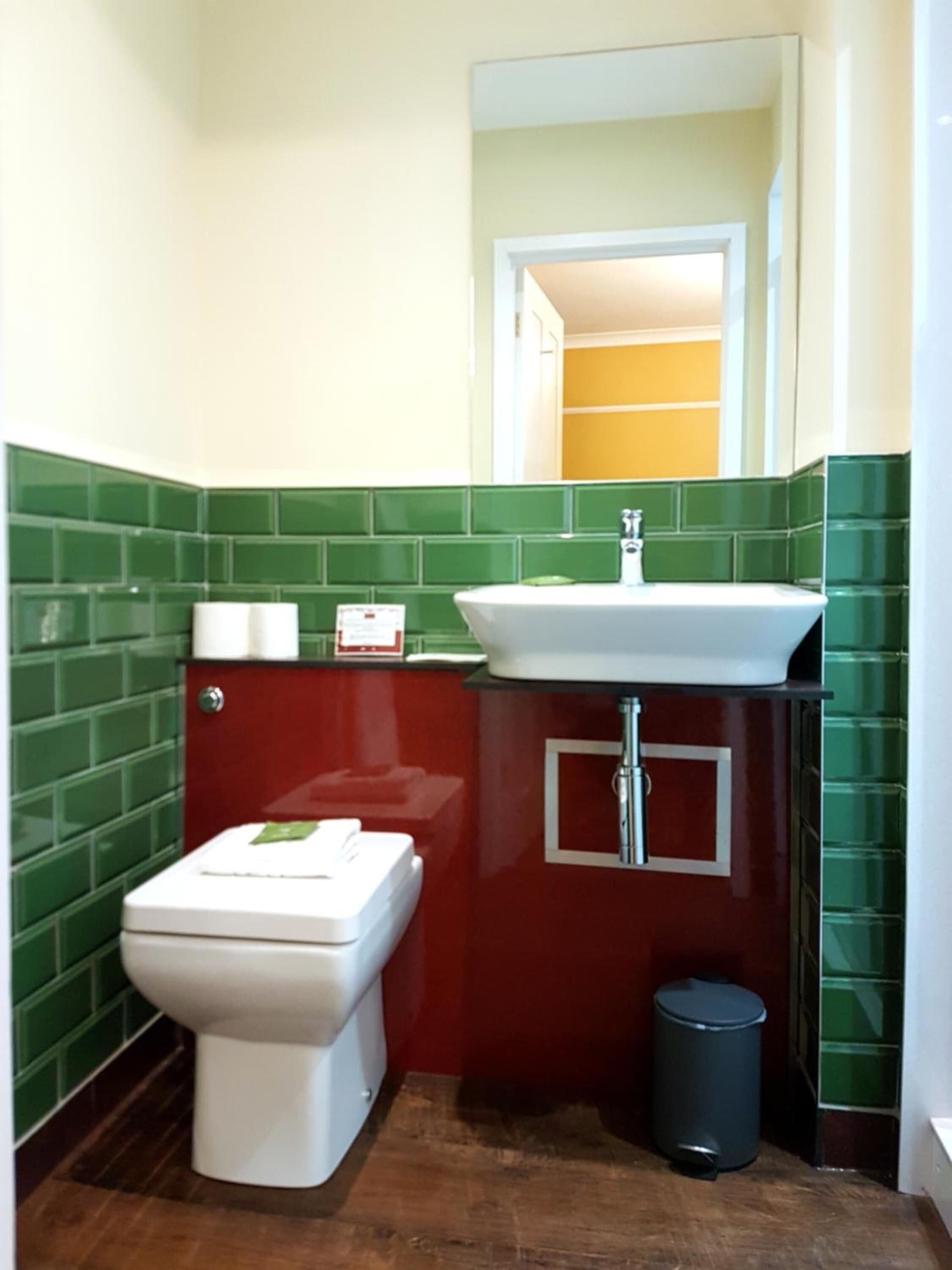 A small bathroom with a toilet, sink, and trash can.