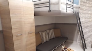A compact room with a bunk bed, a sofa, a small table with a candle, and a ladder. - Central Cozy Cute Downtown Studio 1BR (Athens)