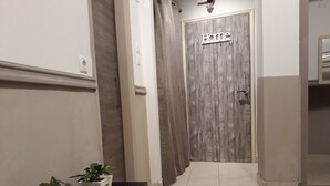 A hallway with a 'Home' sign on a wooden door, a black bench with potted plants, and a tiled floor. - Central Cozy Cute Downtown Studio 1BR (Athens)