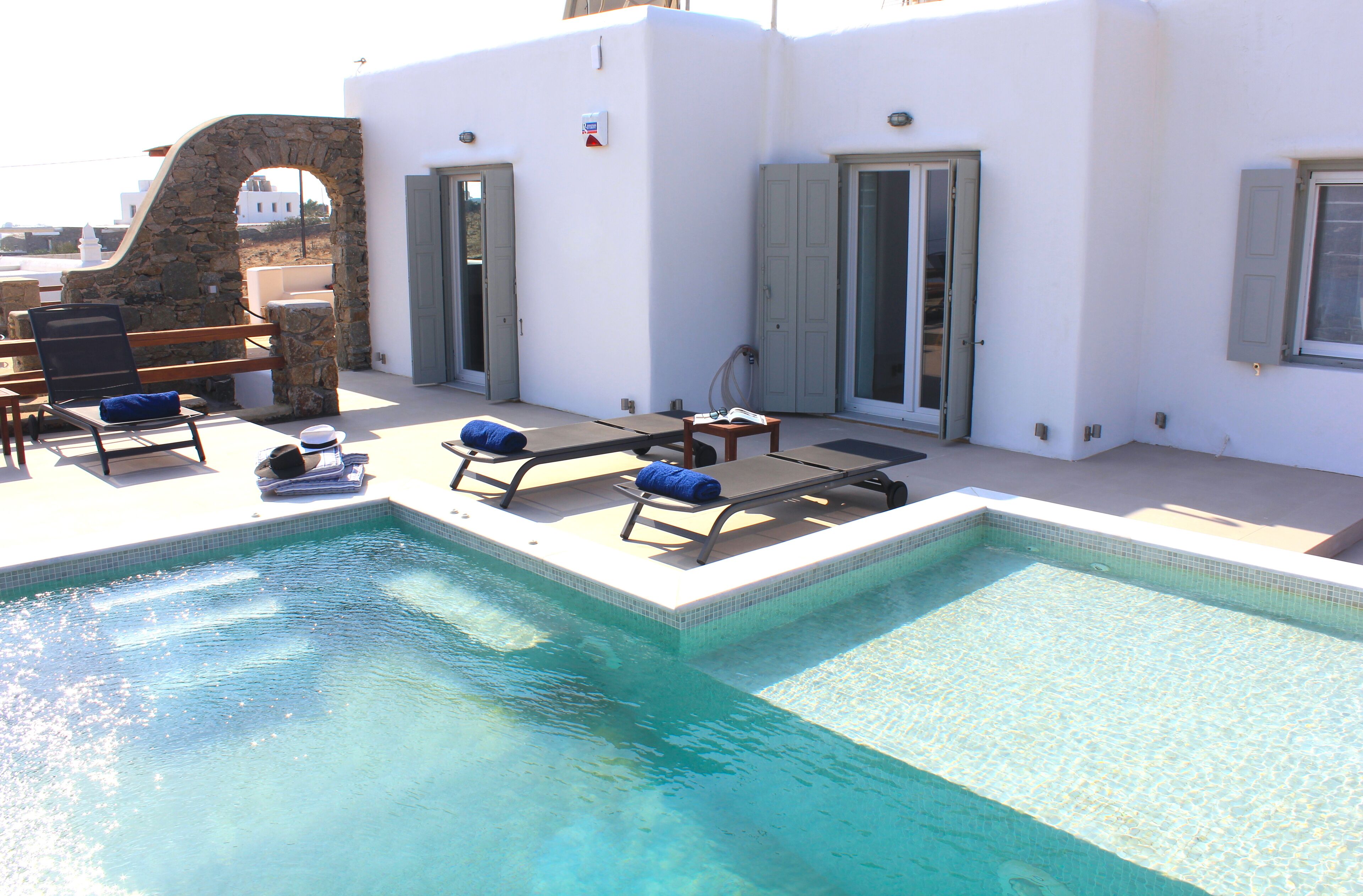 A swimming pool with lounge chairs and a stone archway.