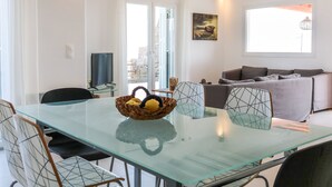 Una sala de estar moderna con una mesa de comedor de vidrio, un sofá gris y un cesto de limones.