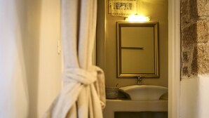 Baño con lavamanos, espejo y toalla colgada en la pared.