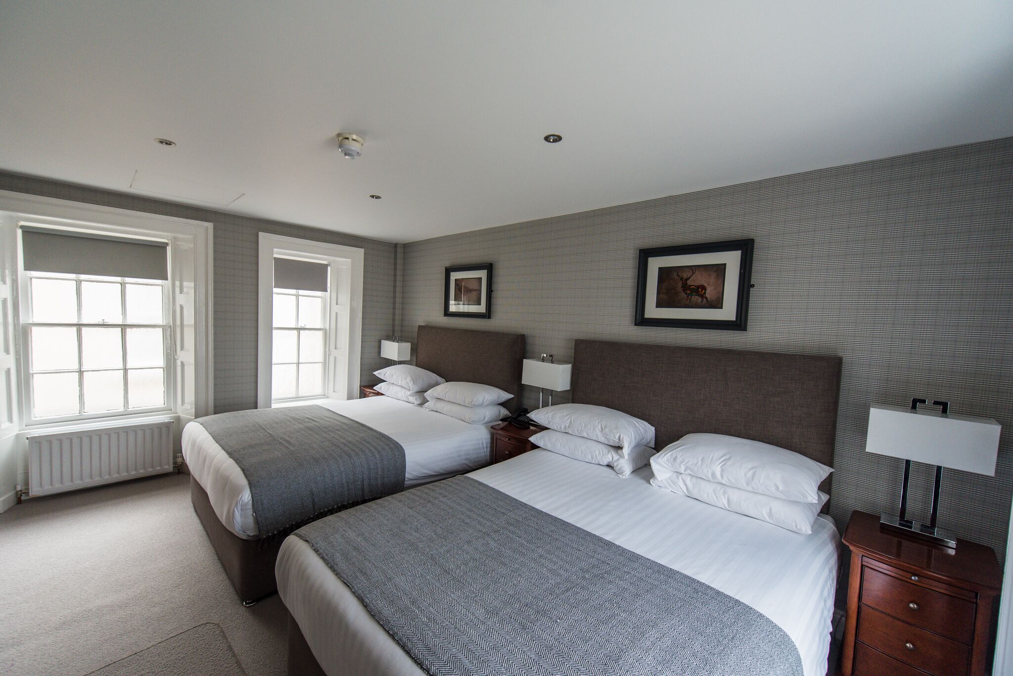 Een hotelkamer met twee bedden, een groot raam en een radiator.