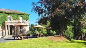 A building with ivy-covered walls, outdoor seating with umbrellas, and a grassy area. - Belmont House Hotel (Banbridge)